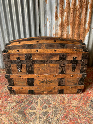 An oak dome top steamer trunk with tooled leather motifs