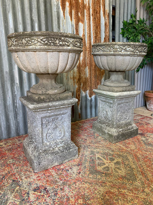 A pair of large cast stone classical urns on pedestals