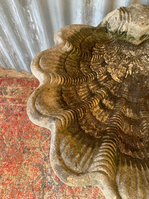 A cast stone bird bath in the form of a shell