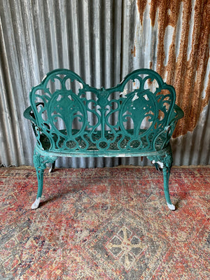 A green cast metal rose motif garden bench