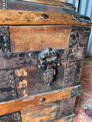 An oak dome top steamer trunk with tooled leather motifs