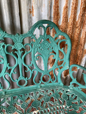 A green cast metal rose motif garden bench