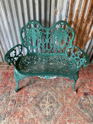 A green cast metal rose motif garden bench