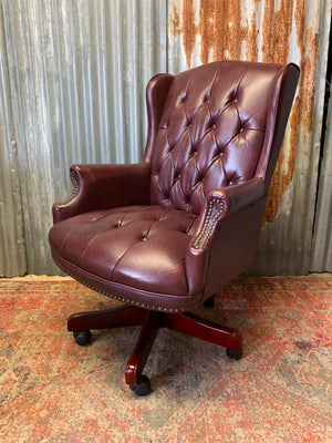 A burgundy leather full button tilt and swivel desk chair
