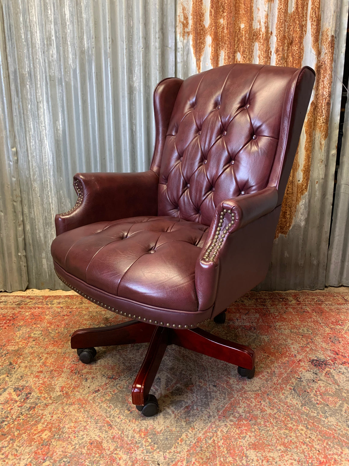 A burgundy leather full button tilt and swivel desk chair
