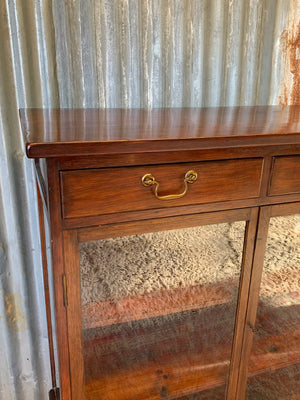 A mahogany double-fronted glass display cabinet with two drawers