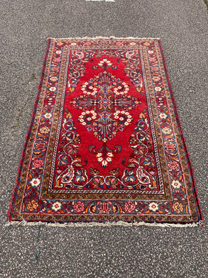 A red ground woolen Persian rug ~ 180cm x 110cm