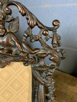 A rococo cast iron easel back frame featuring cherubs