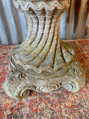 A cast stone bird bath in the form of a shell