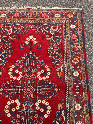 A red ground woolen Persian rug ~ 180cm x 110cm