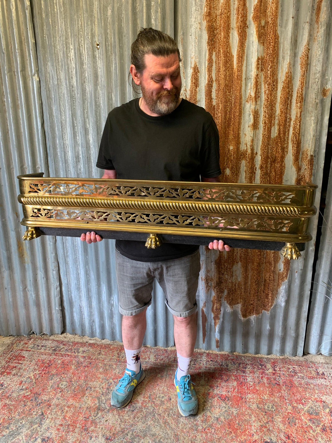 A large Victorian brass fender with lion paw feet