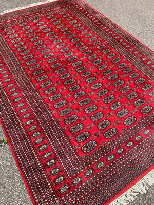 A large red ground Bokhara rectangular rug ~ 282cm x 186cm