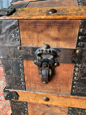 An oak dome top steamer trunk with tooled leather motifs