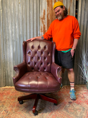A burgundy leather full button tilt and swivel desk chair