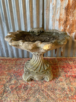 A cast stone bird bath in the form of a shell