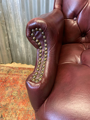 A burgundy leather full button tilt and swivel desk chair