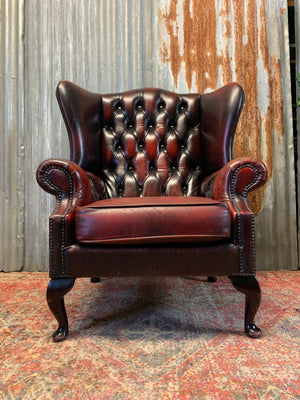 An oxblood wingback Queen Anne-style armchair