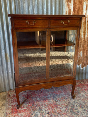 A mahogany double-fronted glass display cabinet with two drawers