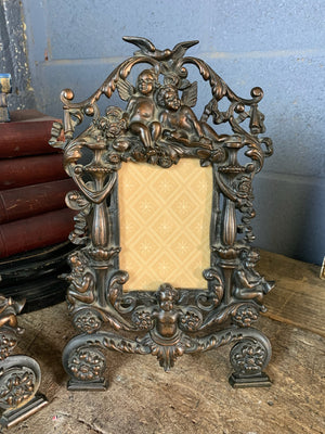 A rococo cast iron easel back frame featuring cherubs