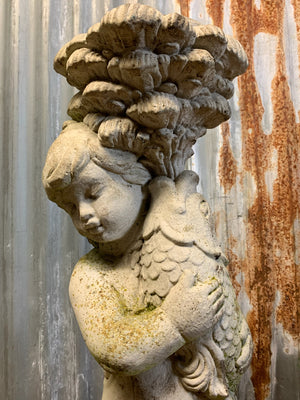 A neoclassical cast stone birdbath with cherub and fish design