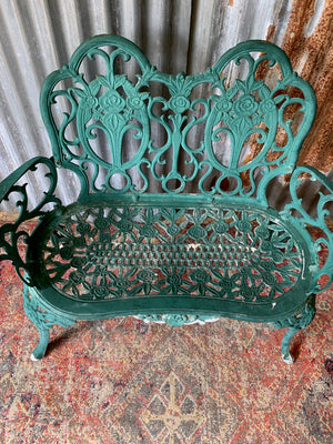 A green cast metal rose motif garden bench