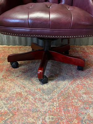 A burgundy leather full button tilt and swivel desk chair
