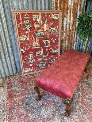 A large red velvet ball and claw footstool