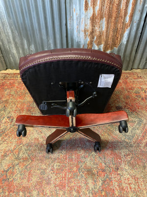 A burgundy leather full button tilt and swivel desk chair