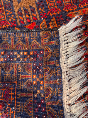 A rectangular red ground Belouch Herat rug depicting lions, camels and birds