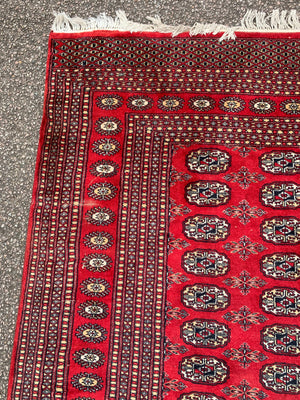 A large red ground Bokhara rectangular rug ~ 282cm x 186cm