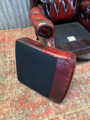 An oxblood wingback Queen Anne-style armchair