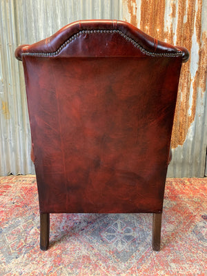 An oxblood wingback Queen Anne-style armchair