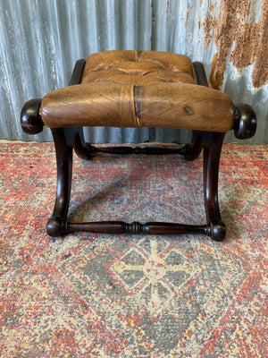 A buttoned tan leather footstool