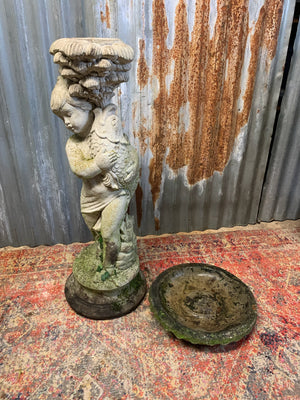 A neoclassical cast stone birdbath with cherub and fish design