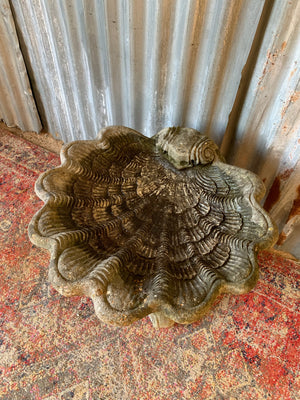 A cast stone bird bath in the form of a shell