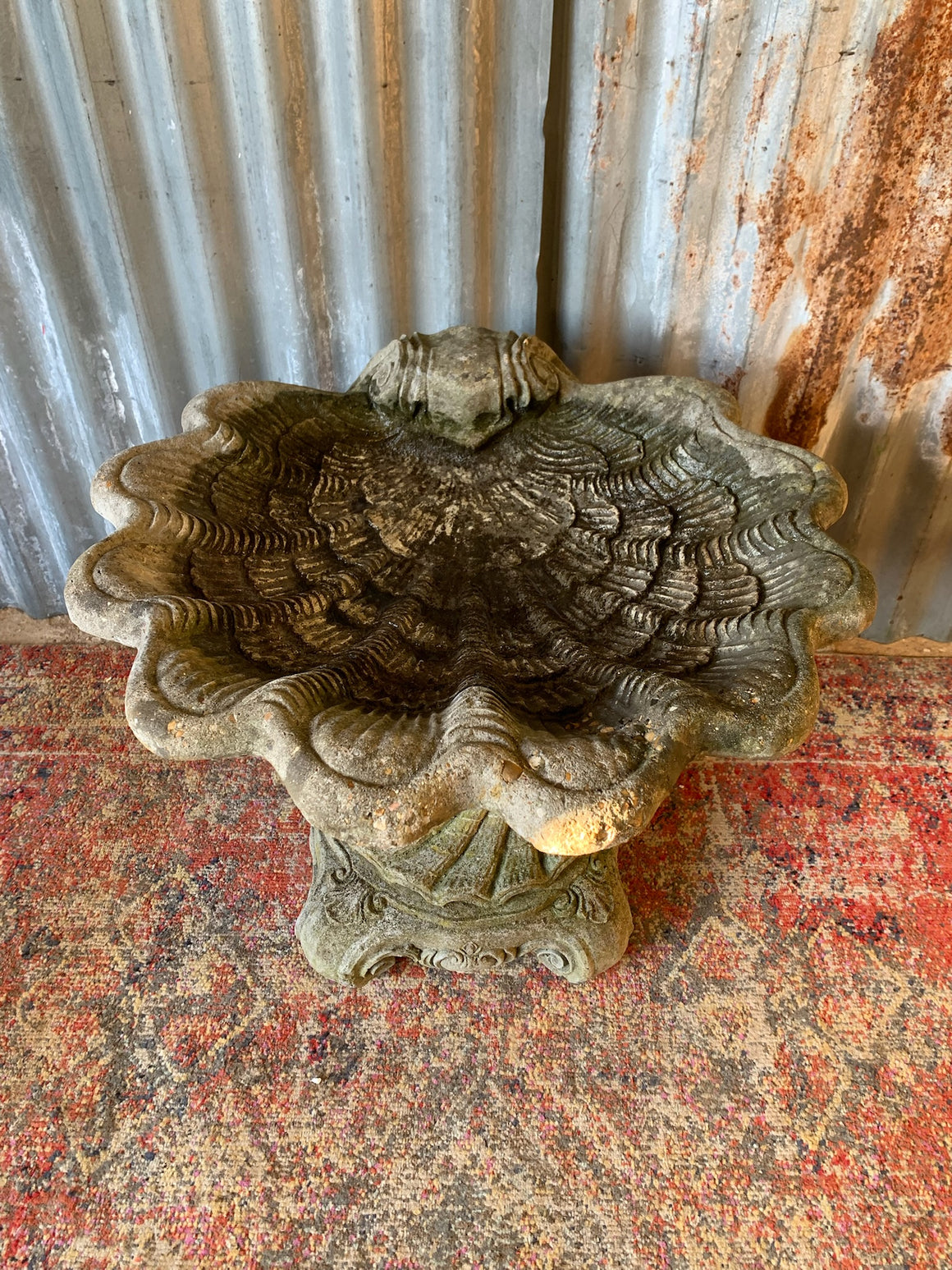 A cast stone bird bath in the form of a shell