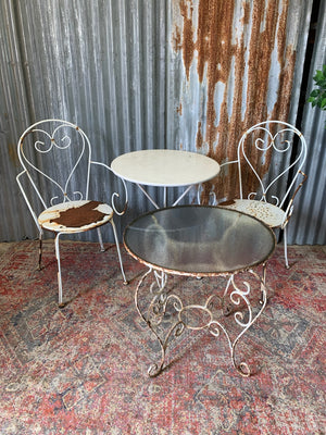 A French-style iron garden table with glass top