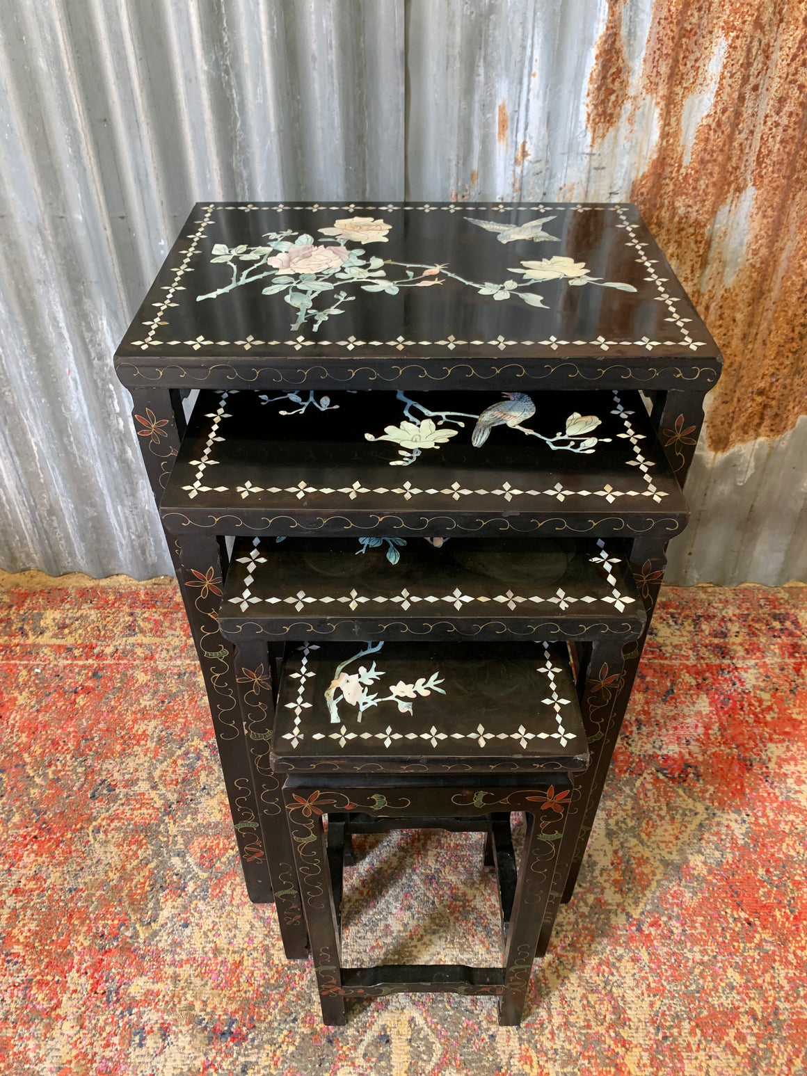 A nest of four black lacquered chinoiserie tables