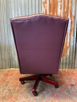 A burgundy leather full button tilt and swivel desk chair