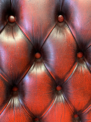 An oxblood wingback Queen Anne-style armchair