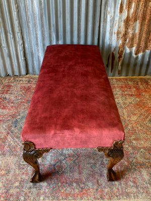 A large red velvet ball and claw footstool