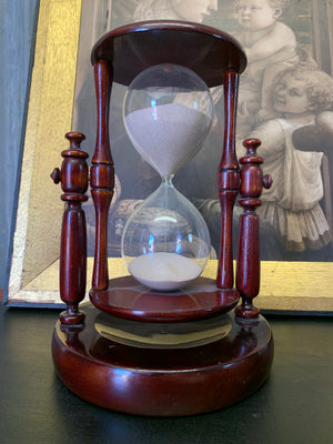A mahogany rotating hourglass or sand timer