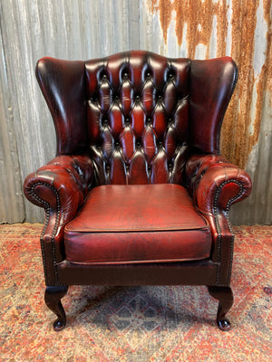 An oxblood wingback Queen Anne-style armchair