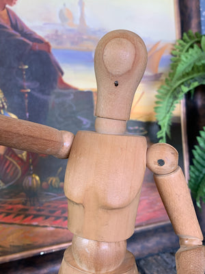 A wooden artist's lay figure mounted on a stand