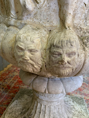 A very large Neoclassical cast stone urn with twin head motif