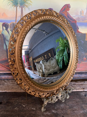 A large gold convex mirror in ornate frame