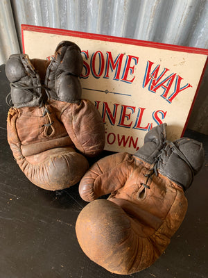 A vintage pair of large brown leather boxing gloves
