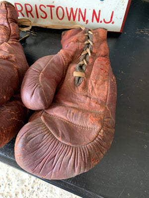 A vintage pair of large red leather boxing gloves