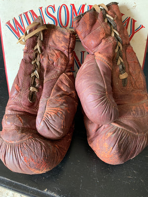 A vintage pair of large red leather boxing gloves