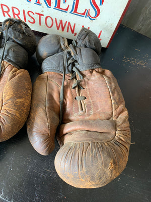 A vintage pair of large brown leather boxing gloves